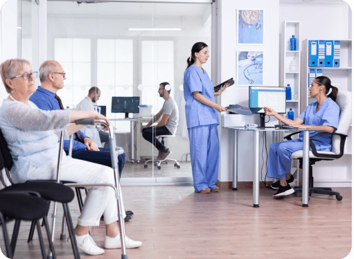 Patients seated in a clinic lobby while medical staff use digital tools at the reception, highlighting nonprofit healthcare services and community health support.