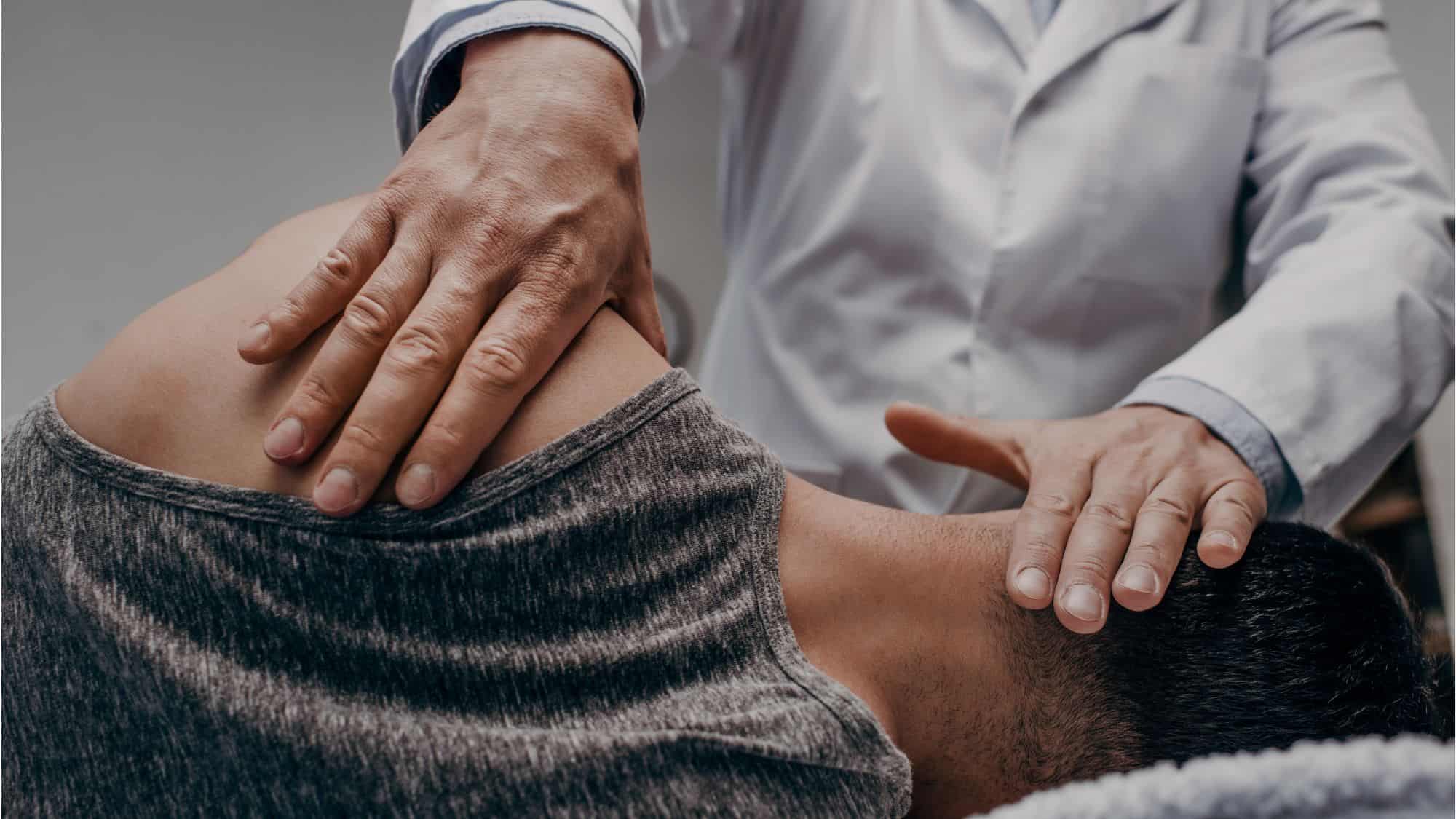 Close-up of a chiropractor's hands performing an adjustment on a patient, emphasizing care and precision, used in a post about effective QR code advertising in chiropractic marketing.