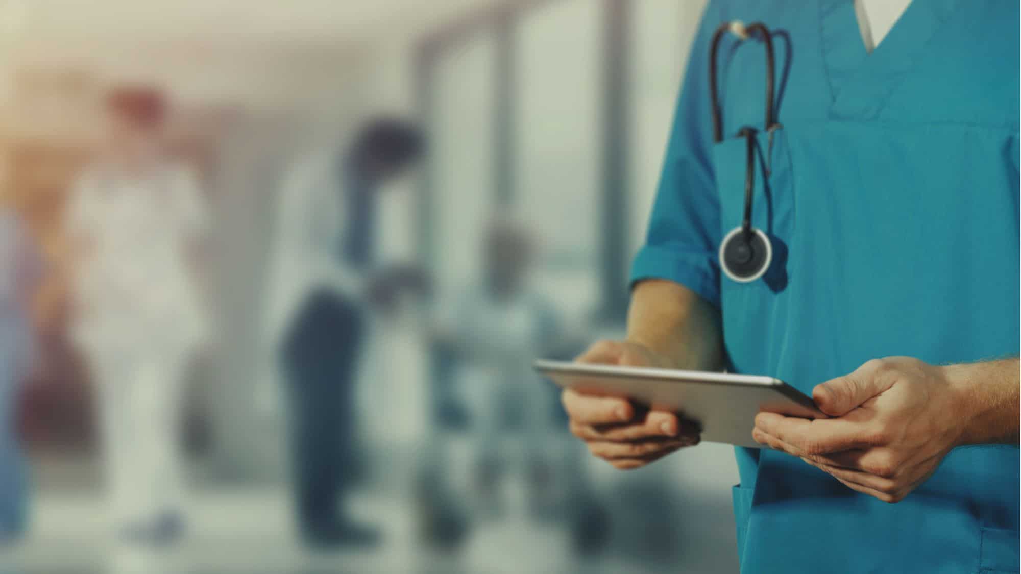 Healthcare professional in scrubs holding a tablet, symbolizing the use of technology like QR codes to improve patient care.